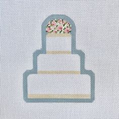 a cake with flowers on top is shown in the cross stitch pattern, and it appears to be made out of white fabric