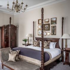 a bedroom with a four poster bed, chandelier and pictures on the wall