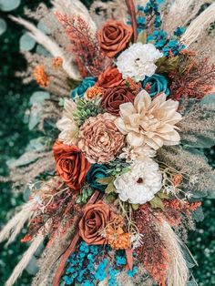 the bridal bouquet is adorned with feathers, flowers and foliages for an autumn wedding