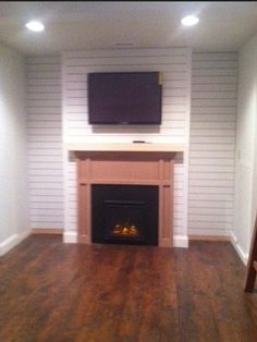 an empty living room with a fireplace and flat screen tv on the wall above it