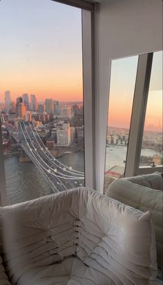 a couch sitting in front of a window overlooking a bridge and the cityscape