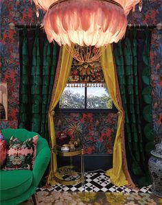 a green chair sitting in front of a window next to a table with a lamp on top of it