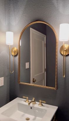 a bathroom sink under a large mirror in front of a light fixture and two lights