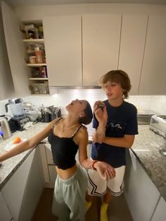 two young women standing in a kitchen with their mouths open and one holding an apple