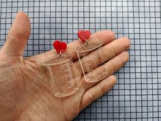 Do you love chemistry? Know someone who does? These super cool beaker earrings are fabulous for a chemistry lover! The beaker is etched and cut from a clear acrylic and hangs from a bold red heart.  They measure 2.2 inches (5.5cm) from top to bottom. There is also a set of conical flask earrings available.  The earrings posts are surgical steel and are paired with surgical steel butterfly backs. These earrings also come with swirly glitter earring tops. Look for them in store! Earring Tops, Conical Flask, Quirky Earrings, Glitter Earrings, Laser Cut Acrylic, Laser Cut Wood, Acrylic Earrings, Super Cool, Red Heart