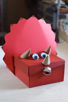 a red box with an animal's head sticking out of it and the words dinosaur ticeratops valentines box to treasure box craft