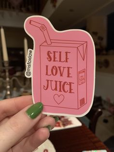 someone holding up a pink sticker with the words self love juice in front of them