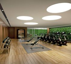 a gym with rows of exercise equipment and green wall in the backround area