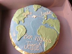 a blue and green cake in a box with the name bon voyage written on it