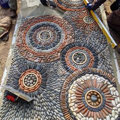 two men are working on a mosaic design with stone and brick circles in the center