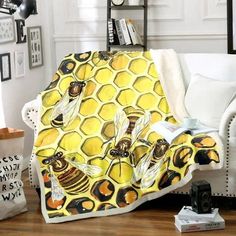 a yellow and black blanket with two bees sitting on it's sides next to a white couch