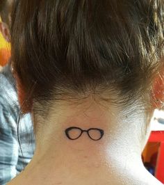 a woman's neck tattoo with glasses on the back of her left side ribcage