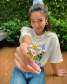 a girl is holding a flower in her hand