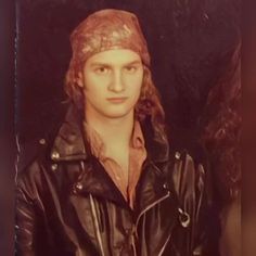 an old photo of a young man wearing a leather jacket and hat with long hair