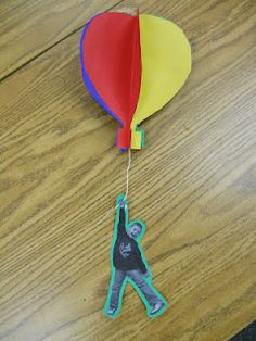 a kite shaped like a man with a balloon attached to it on top of a wooden table