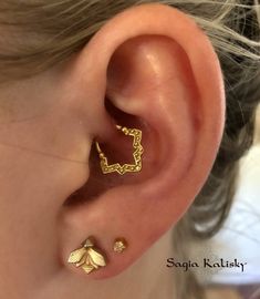 a close up of a person's ear with two small gold leaves on it