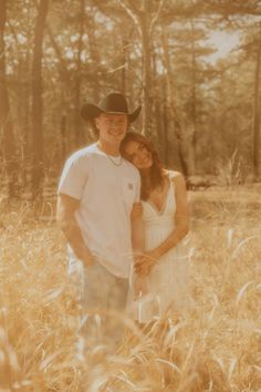 a man and woman are standing in the tall grass with their arms around each other