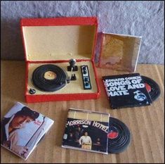 various records and cds in a red box on a wooden table next to a record player