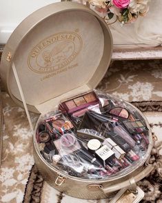 an open suitcase filled with lots of makeup and eyeliners on top of a rug