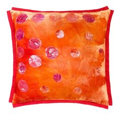 an orange and red pillow with pink circles on it