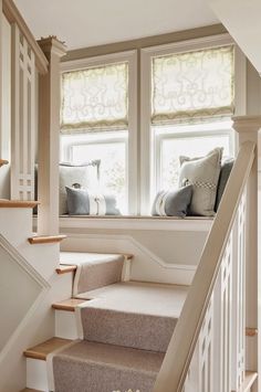 the stairs lead up to two windows with pillows on them, along with carpeted flooring