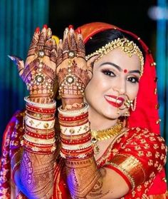 a woman in red and gold is holding her hands up to show the hendi