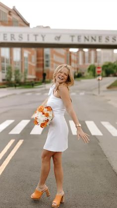 a woman in a white dress is walking across the street with her hands out and smiling