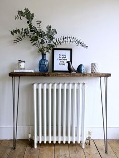 a white radiator sitting on top of a wooden table next to a plant