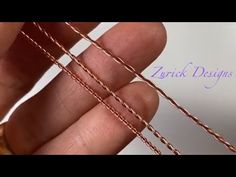 a hand holding a piece of copper wire