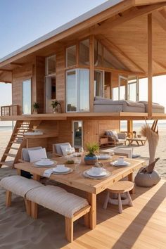 a wooden house on the beach with an outdoor dining table and bench in front of it