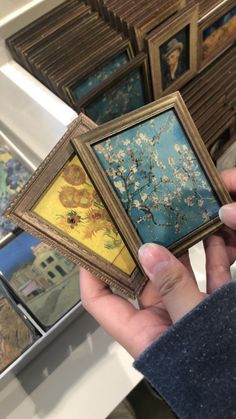 a person holding up some paintings in their hands