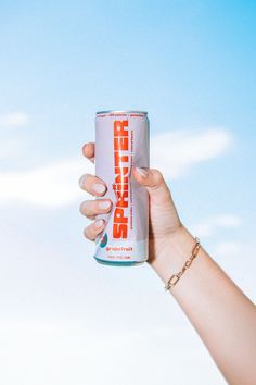 a hand holding up a can of spriter energy drink against a blue sky