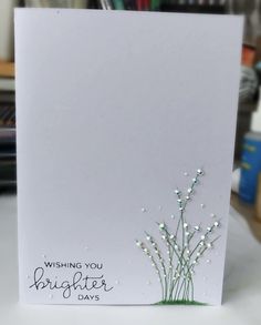 a white card with some flowers and writing on the front that says wishing you brighter days