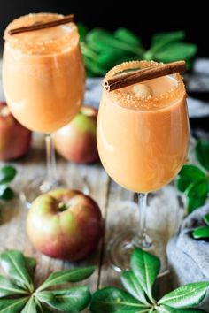 two glasses filled with apple cider on top of a table