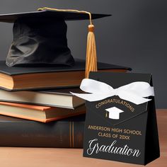 graduation cap and diploma on top of books with congratulations tag attached to the book cover