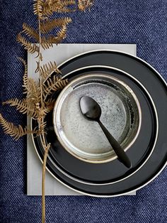 an empty plate with a spoon on top of it next to a fork and plant