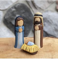 two nativity figurines sitting on top of a wooden table