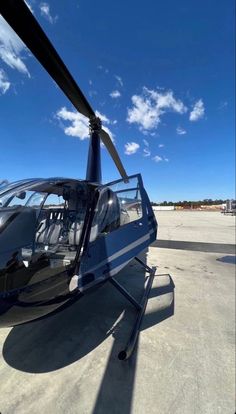 a helicopter sitting on top of an airport tarmac next to a blue sky with clouds