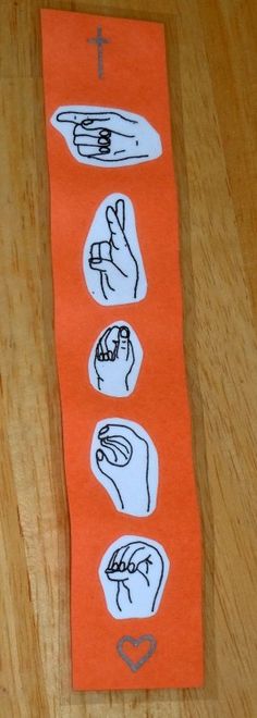 an orange piece of paper with pictures of hands and fingers on it sitting on top of a wooden table