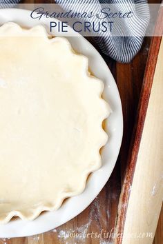 a pie crust sitting on top of a white plate next to a wooden spatula