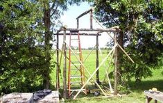 a wooden structure sitting in the middle of a lush green field