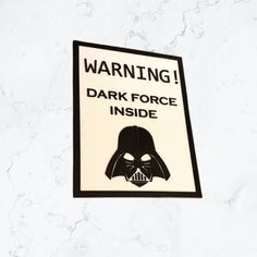 a darth vader warning sign on the side of a white wall with black lettering