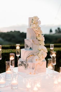 a wedding cake with white flowers and candles