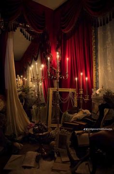 a room filled with lots of furniture and candles on the wall next to red drapes