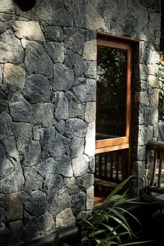 a wooden bench sitting in front of a stone wall next to a window and door