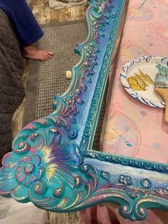 an ornate blue mirror sitting on top of a wooden table next to a pink wall