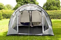 a tent set up in the grass with its door open to reveal a bed inside