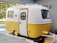 a yellow and white trailer parked next to a building