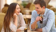 a man and woman sitting at a table with drinks in front of them, looking into each others eyes