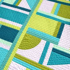 a close up of a quilt on a bed with blue, yellow and green colors